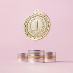 A gold medal and stacks of coins on a light pink backdrop, symbolizing victory and wealth.